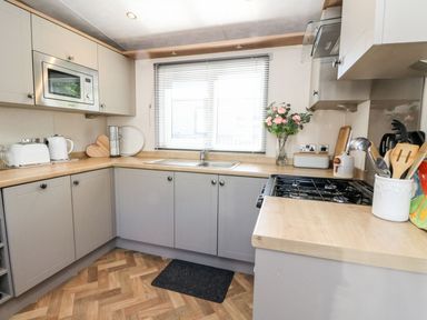 A kitchen with grey cabinets wooden countertops a microwave stove and utensils at Saorsa in St Fillans