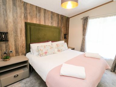 A bedroom with a bed that has a green headboard and floral pillows at Saorsa in St Fillans
