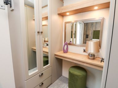 A dressing area with a mirror above a wooden countertop and a green stool at Saorsa in St Fillans