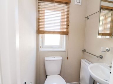 A small bathroom with a toilet sink radiator window with blinds at Saorsa in St Fillans