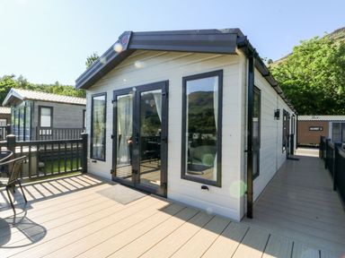 A small house with large windows and a wooden deck with outdoor furniture at Saorsa in St Fillans