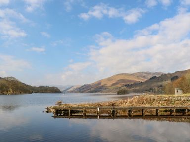 A lake with a wooden dock and hills in the background at Saorsa in St Fillans