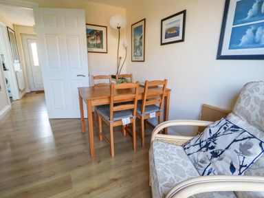 A dining area with a wooden table and four chairs next to an armchair with patterned cushions at 74 Reap Lane Southwell near Weston