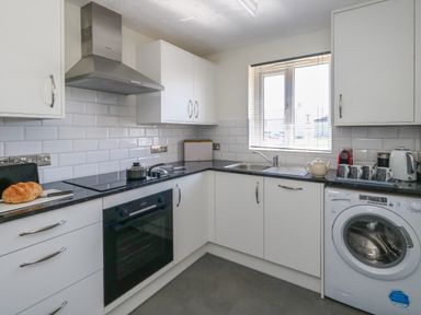 A kitchen with white cabinets a black countertop and a washing machine at 74 Reap Lane Southwell near Weston