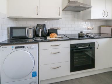 A kitchen counter with a microwave toaster air fryer loaf of bread electric stove oven and washing machine at 74 Reap Lane Southwell near Weston