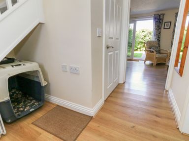 A hallway with a pet crate under the staircase and a chair visible in the adjoining room at 74 Reap Lane Southwell near Weston
