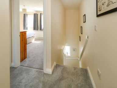 A stair landing with carpet leading to a bedroom with curtains and a chest of drawers at 74 Reap Lane Southwell near Weston