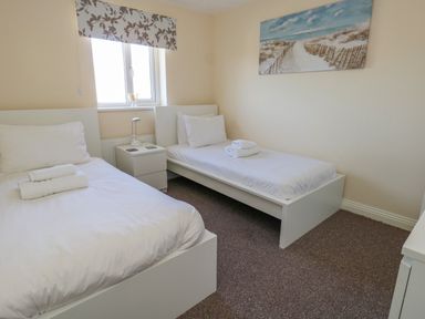 A bedroom with two single beds bedside table and a window at 74 Reap Lane Southwell near Weston