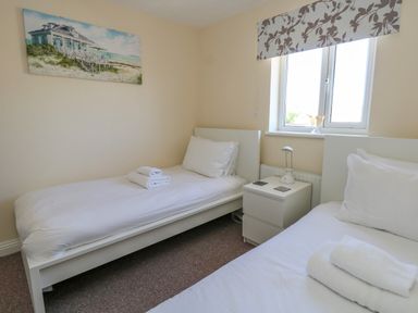 A bedroom with two single beds a nightstand with a lamp between the beds and a beach house painting on the wall at 74 Reap Lane Southwell near Weston