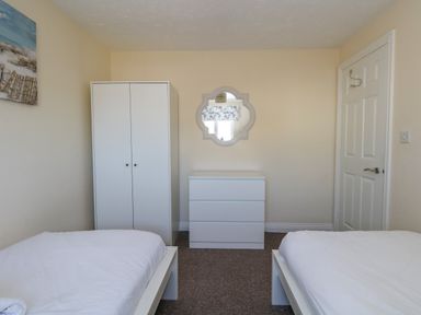 A bedroom with two single beds a white wardrobe a white chest of drawers and a decorative mirror at 74 Reap Lane Southwell near Weston