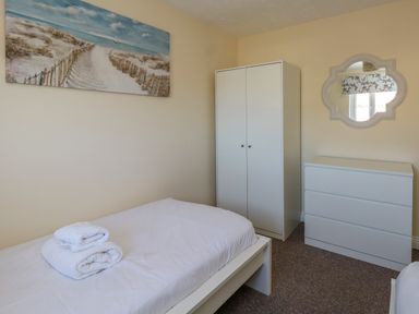 A bedroom with a single bed white wardrobe white chest of drawers and a beach pathway painting on the wall at 74 Reap Lane in Southwell near Weston
