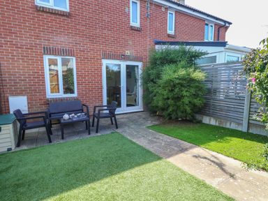A backyard with artificial grass patio furniture and bushes at 74 Reap Lane Southwell near Weston
