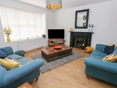 A living room with teal sofas wooden coffee table and television at Bryn Siriol in Narberth