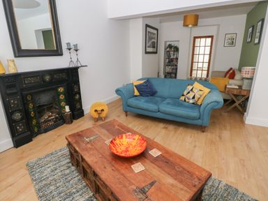A living room with a blue sofa wooden coffee table and a fireplace at Bryn Siriol in Narberth
