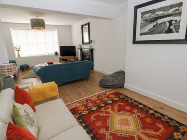 A living room with sofas a patterned rug a TV on a stand and a framed picture on the wall at Bryn Siriol in Narberth