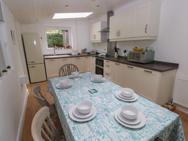 A kitchen with cream cabinets a table set for six and a refrigerator at Bryn Siriol Narberth