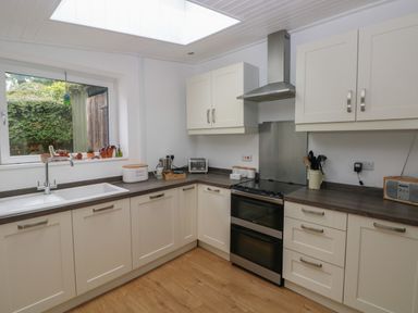 A kitchen with white cabinets a sink a stove and countertop items at Bryn Siriol in Narberth