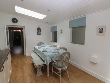 A dining room with a table set for six including four chairs and a bench at Bryn Siriol in Narberth
