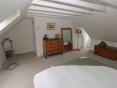 A bedroom with a bed wooden chest dresser standing mirror and clothes rack at Bryn Siriol in Narberth