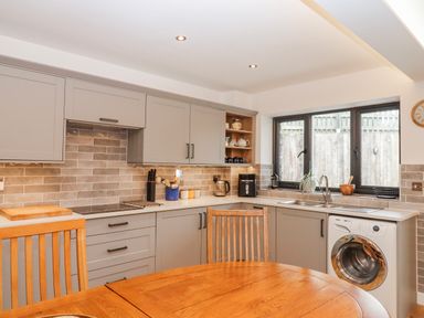 A kitchen with cabinets and a washing machine at Lower Moorwood in Moorwood near Bovey Tracey