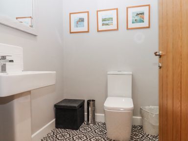 A bathroom with a toilet, sink, and framed pictures at Lower Moorwood Moorwood near Bovey Tracey