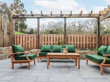 An outdoor patio with green seating and a coffee table at Lower Moorwood in Moorwood near Bovey Tracey