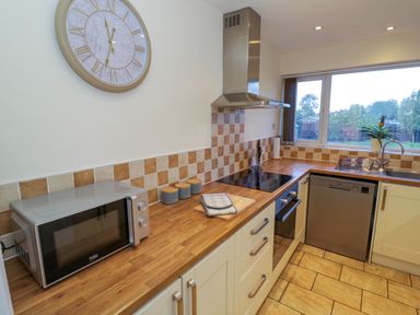 A kitchen with a microwave oven stovetop dishwasher and sink at Fenny Marina Cottage in Fenny Bentley