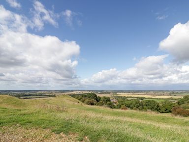 A rural landscape with grassy fields trees and a partly cloudy sky at Fenny Marina Cottage in Fenny Bentley