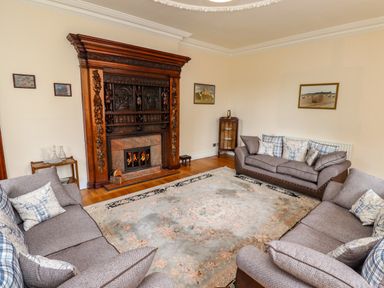 A living room with three sofas and a fireplace at North Wing Middleton Hall Estate near Belford