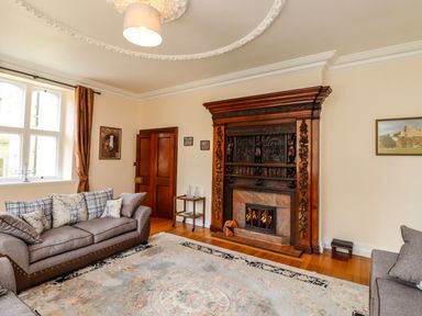 A living room with sofas a patterned rug and a carved wooden fireplace at North Wing in Middleton Hall Estate near Belford