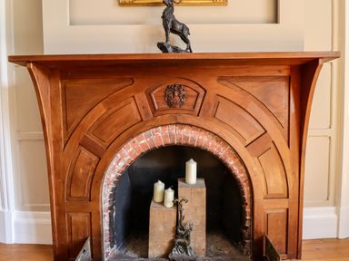 A wooden fireplace mantel with a brick arch interior holding three candles and a metal decorative piece at North Wing Middleton Hall Estate near Belford