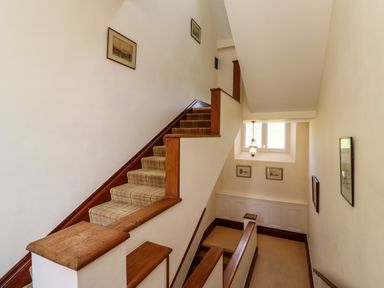 A stairway with wooden handrails and plaid carpet on stairs with framed pictures on the walls at North Wing in Middleton Hall Estate near Belford
