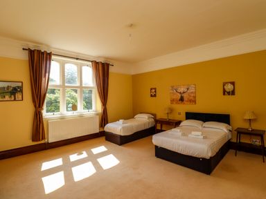 A bedroom with two beds bedside tables lamps and curtains at North Wing in Middleton Hall Estate near Belford