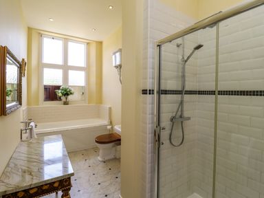 A bathroom with a bathtub a shower a toilet with a wooden seat and a marble countertop at North Wing in Middleton Hall Estate near Belford