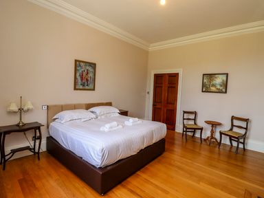 A bedroom with a double bed two chairs and a side table at North Wing in Middleton Hall Estate near Belford