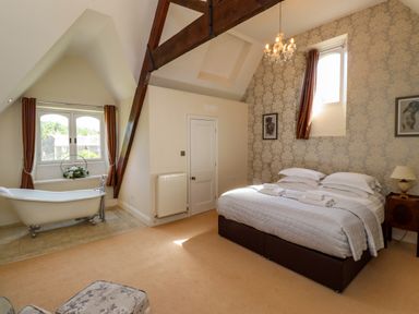 A bedroom with a bed two framed pictures a chandelier and a bathtub near a window at North Wing in Middleton Hall Estate near Belford