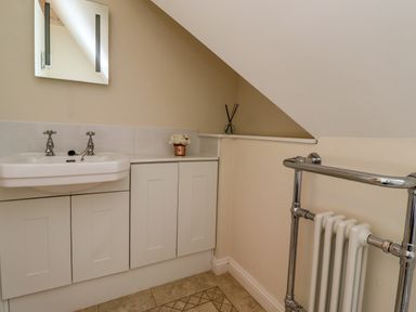 A bathroom sink with cabinet under and a mirror above with a towel rail radiator on the right at North Wing in Middleton Hall Estate near Belford