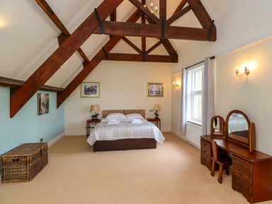 A bedroom with exposed wooden beams a bed a dressing table and a wicker chest at North Wing in Middleton Hall Estate near Belford