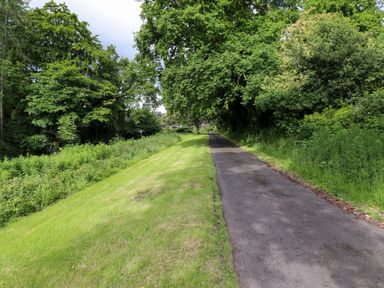 A paved pathway with grass and trees on both sides at North Wing in Middleton Hall Estate near Belford