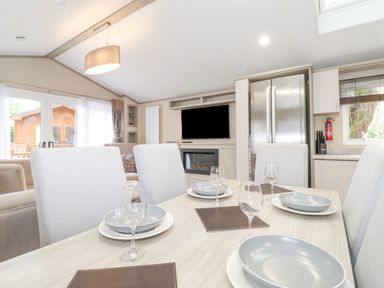 A dining area with a set table beside a kitchen and living room at Tawny Owl Lodge in Coniston 4 White Cross Bay near Windermere