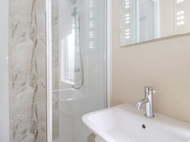 A bathroom with a shower enclosure and a white sink with a faucet at Tawny Owl Lodge Coniston 4 White Cross Bay near Windermere