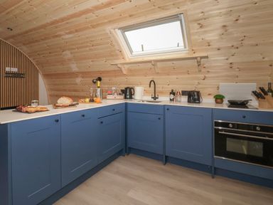 A kitchen with blue cabinets a skylight window a sink toaster oven and food on the countertop at Lapwing in Chapel Le Dale near Ingleton