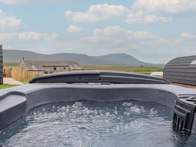 An outdoor hot tub with bubbles and mountains in the background at Lapwing in Chapel Le Dale near Ingleton