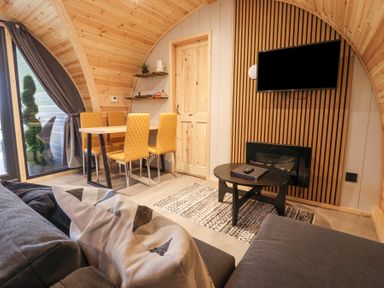 A living room with a dining table and chairs a wall-mounted television and a coffee table at Lapwing Chapel Le Dale near Ingleton