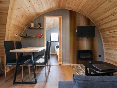 A wooden dining room with a table and four chairs next to a living area with a fireplace and TV at Oyster Catcher in Chapel Le Dale near Ingleton