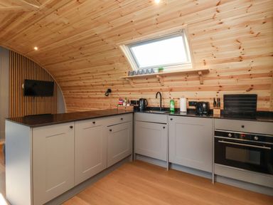 A kitchen with grey cabinets black countertops wooden ceiling and floor with a skylight at Oyster Catcher in Chapel Le Dale near Ingleton