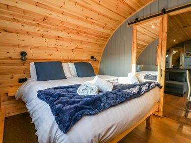 A bedroom with a bed blue pillows and a blue blanket in a wooden pod at Oyster Catcher Chapel Le Dale near Ingleton