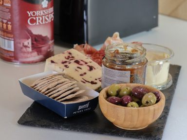 A snack platter with crackers olives chutney cheese and ham with a can of Yorkshire Crisps in the background at Heron Ingleton