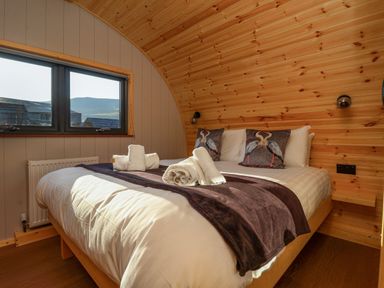 A bedroom with a bed with towels and pillows under a curved wooden ceiling at Heron in Ingleton