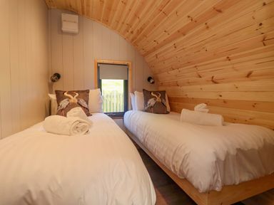 A small bedroom with two single beds and a window with blinds at Heron in Ingleton